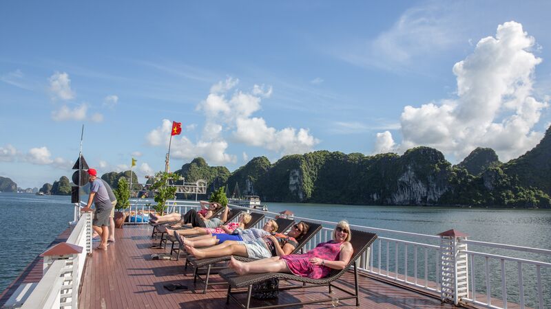 A row of sunbathers on deck in Halong Bay on a sunny day in Vietnam. 