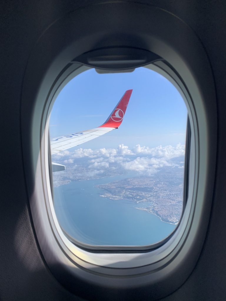View of Turkey's coastline and a plane's wing taken from inside a plane.