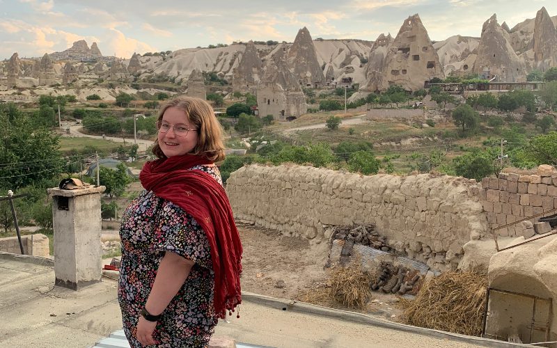 Woman smiles in front of the fairy chimneys in Cappadocia, Turkey