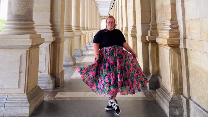 A young woman in a black top and floral skirt