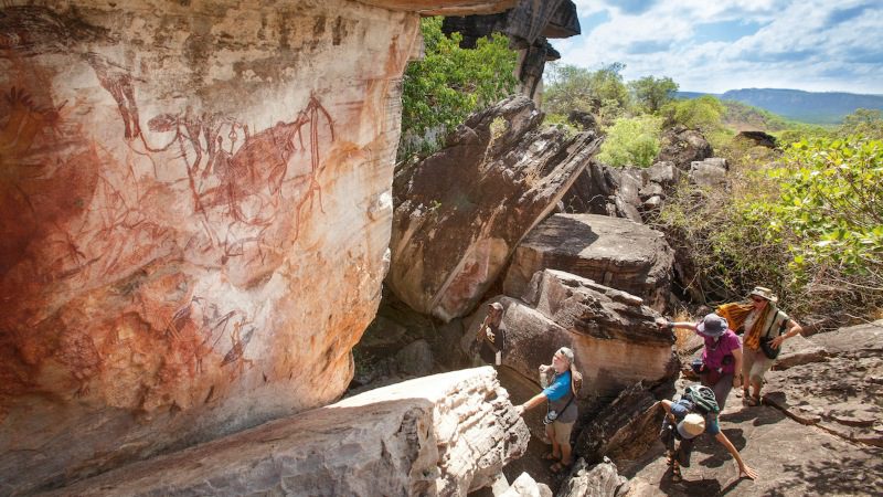 Hikers climb rocks to admire ancient rock art in Australia