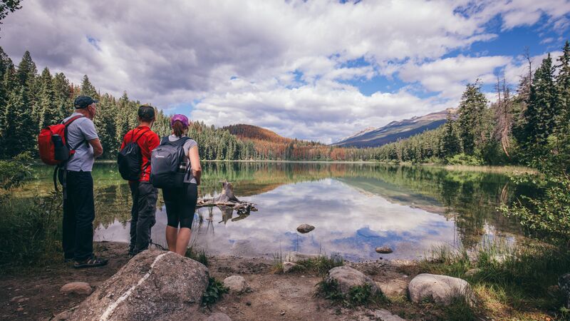 A group of travellers looking out over a reflective lake in Jasper National Park. 
