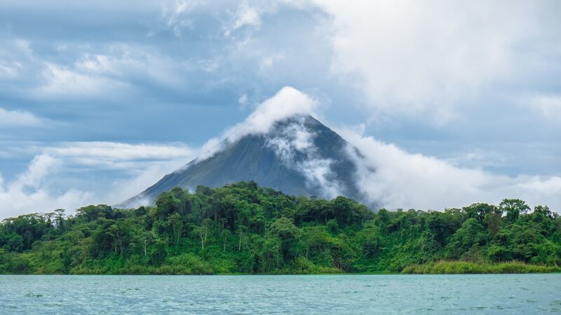 The imposing figure of Arenal Volcano towering over a lush jungle. 