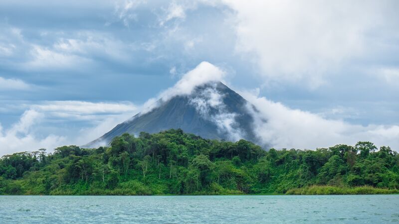The imposing figure of Arenal Volcano towering over a lush jungle.