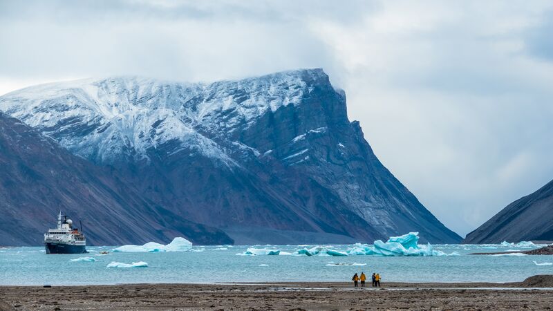 A group of travellers standing on land in front of the waters of the Northwest Passage. 