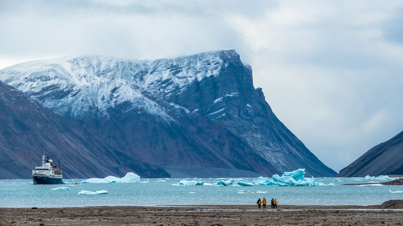 A group of travellers standing on land in front of the waters of the Northwest Passage.