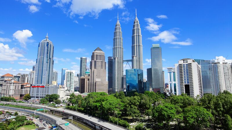 The skyscraper filled skyline of Kuala Lumpur against a blue sky. 