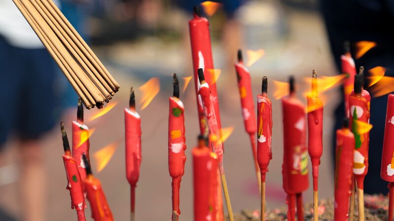 A collection of red candles being lit.