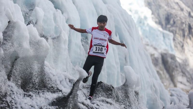 A man trail running through a snowy mountain in Nepal