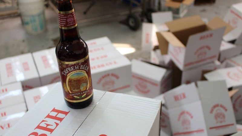 A bottle of beer sitting on a cardboard box, with empty boxes in the background