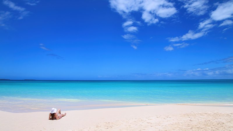 Woman sunbathing on the white sand of Fayaoue Beach in New Caledonia. 