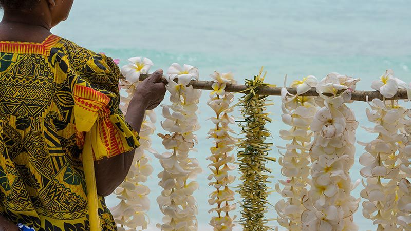 A local woman stringing up frangipani flower necklaces.