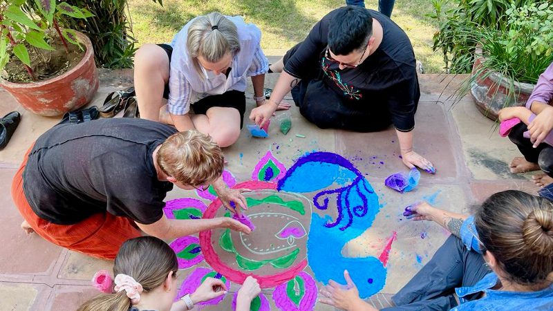 a group of travellers creating a rangoli 