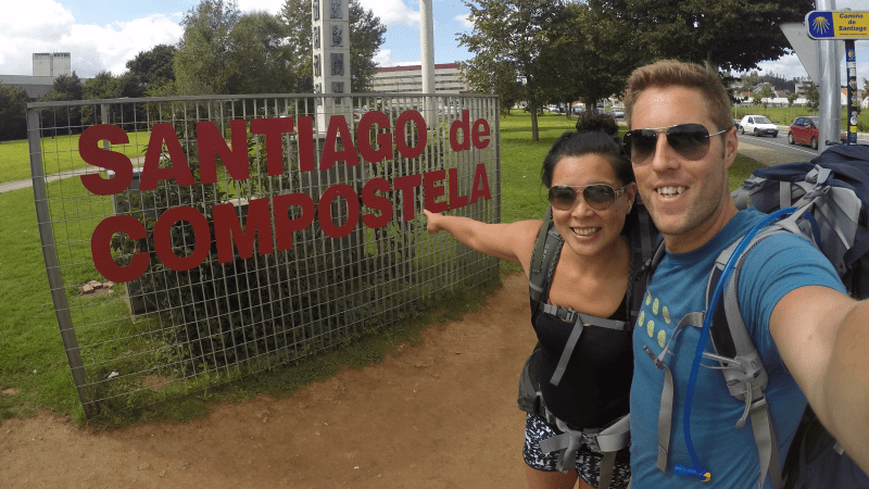 A couple point to a sign reading 'Santiago de Compostela'