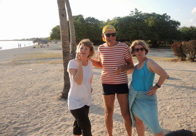 Three travellers pose with cigars on the beach in Cuba