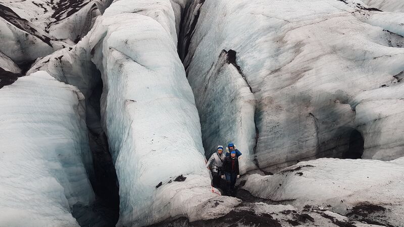 A few travellers standing at the base of an icy glacier in Iceland