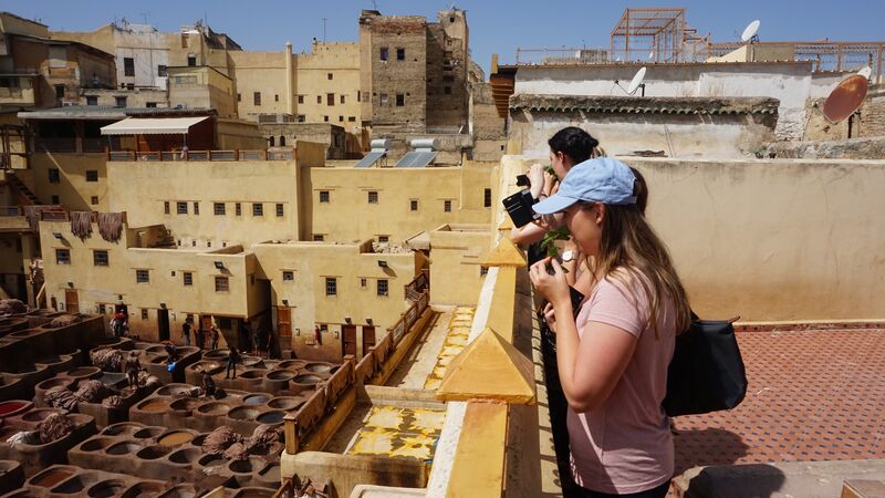 A couple of travellers taking photographs of a traditional dye factory in Morocco. 