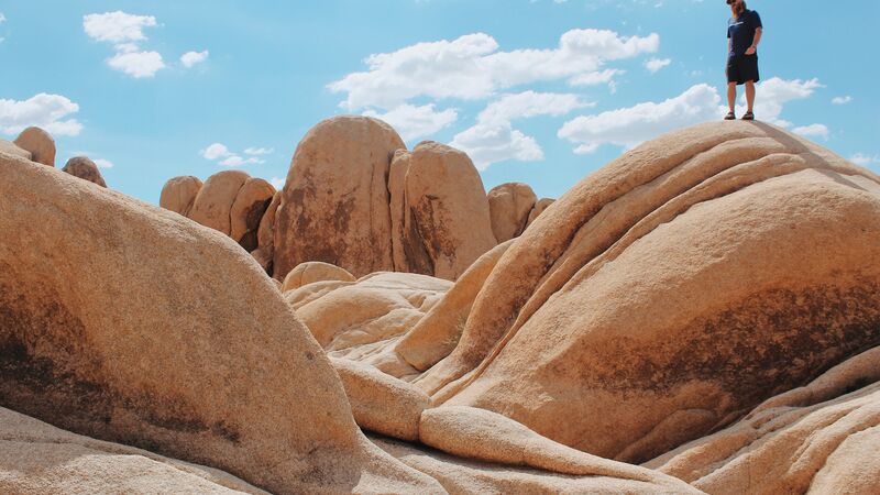 A traveller walking across boulders in Joshua Tree National Park in the USA