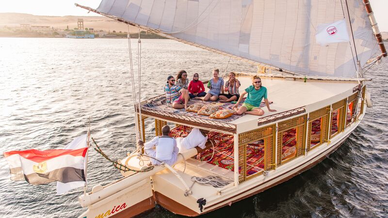 Travellers sitting on the roof of a felucca  as it cruises down the Nile