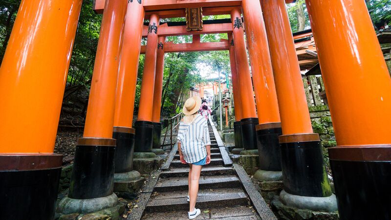 A traveller walking up stairs at Fushimi Inari Shrine in Kyoto, Japan