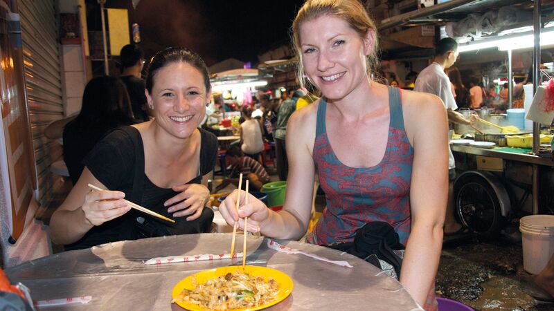 Two travellers enjoying a plate of noodles in Thailand.