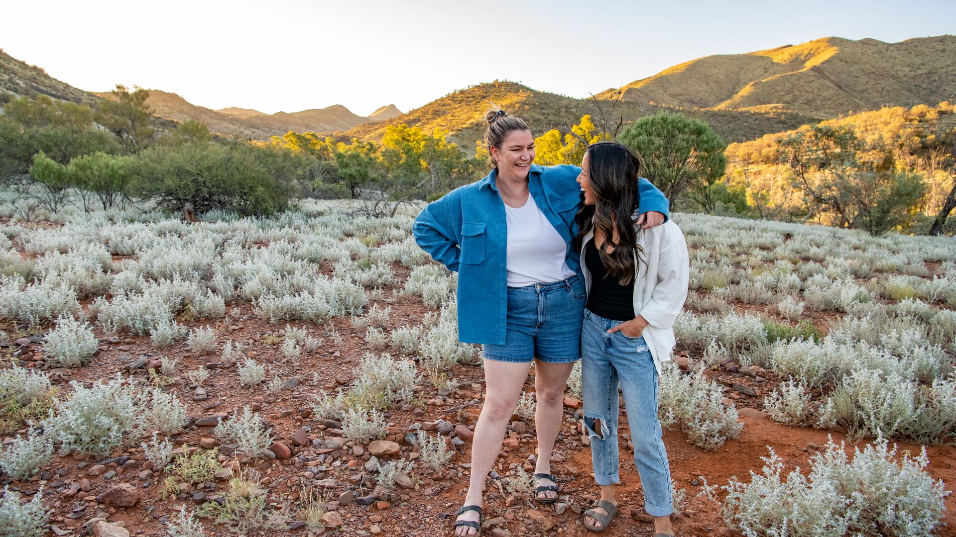 Two women smile and laugh in Arkaroola at sunset.