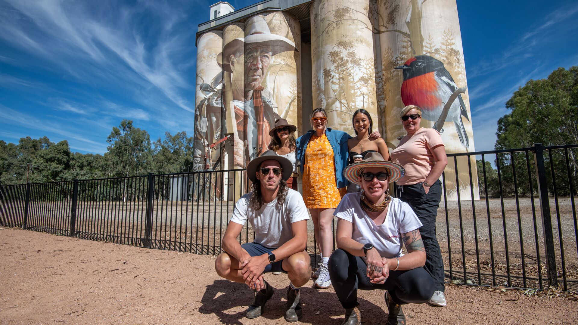 A group smiles in front of the Wirrabarra Silo art.