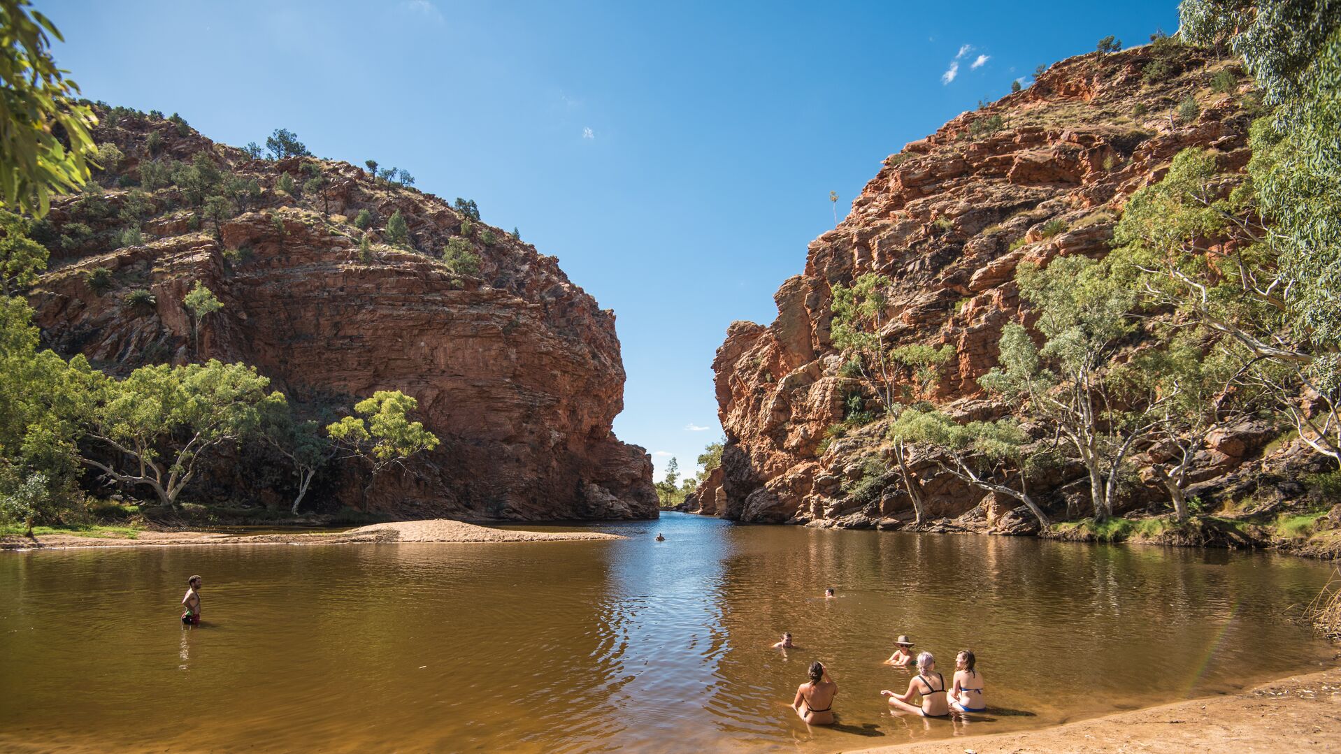 People sit and swim in Ormiston Gorge.