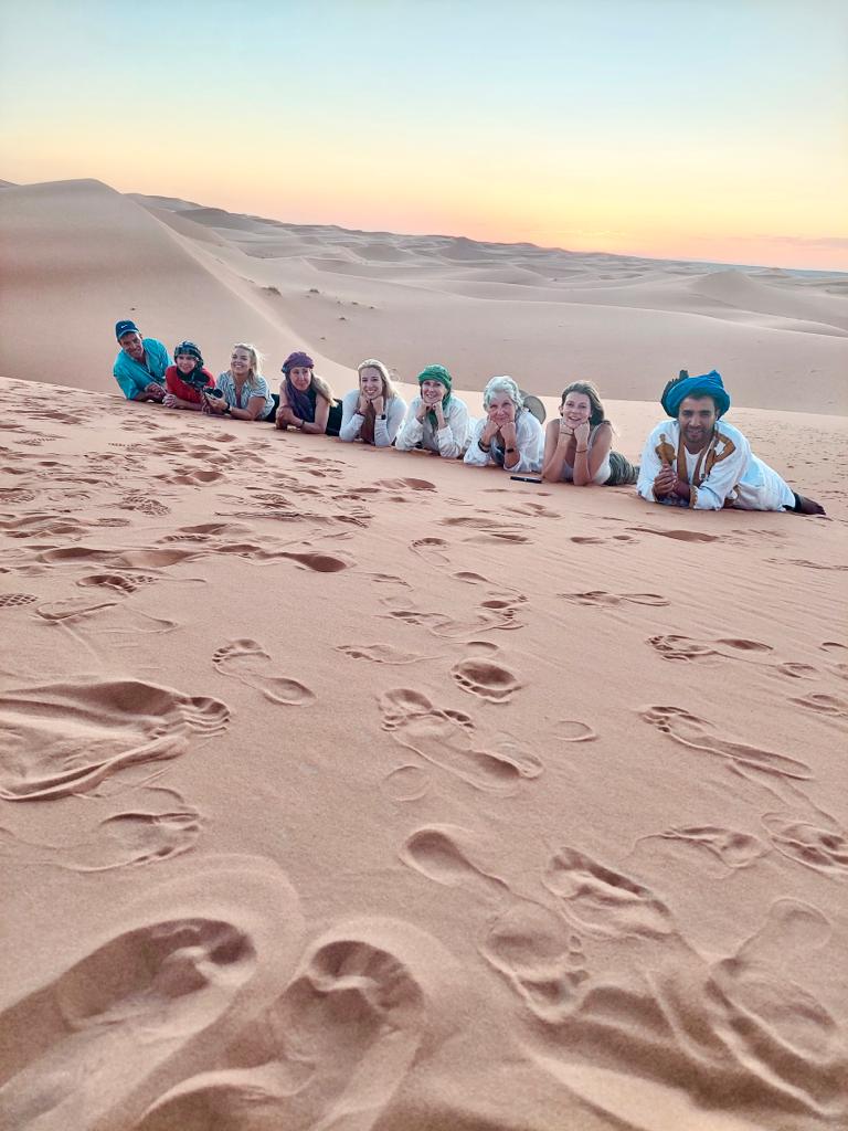 A tour group pose on the sand in the Sahara, Morocco