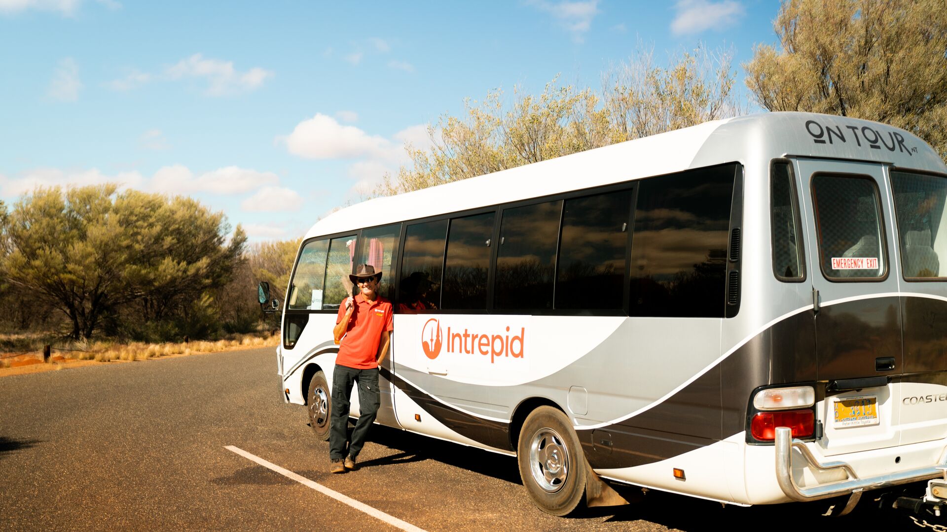 An Intrepid leader standing and smiling by a small coach