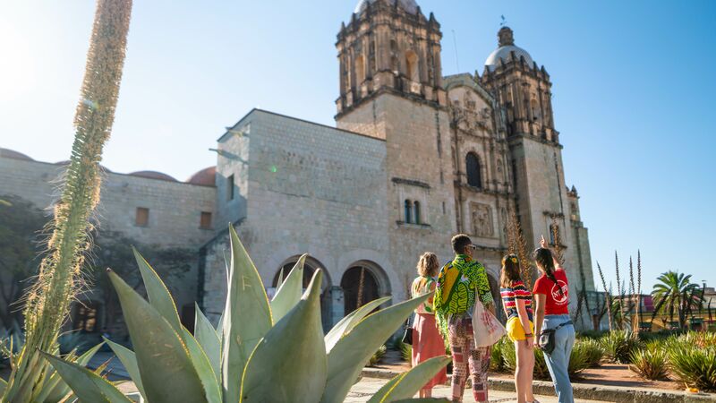 A small group of travellers looking at a Spanish cathedral in Oaxaca.