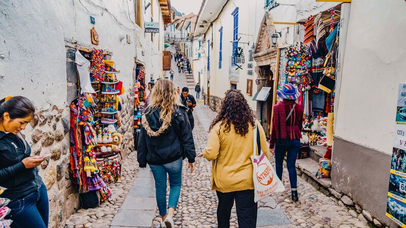 A couple fo travellers walking through the colourful streets of Cusco in Peru.
