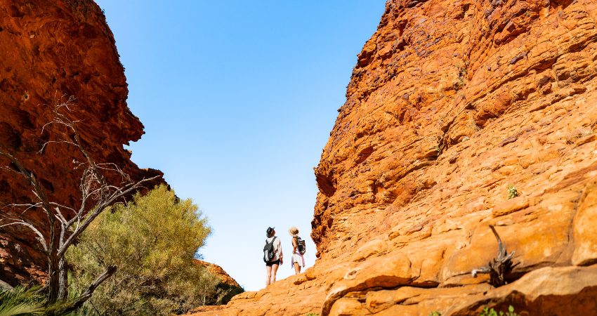 Two travellerrs gazing up at a giant boulder on the Kings Canyon Rim Walk in Australia