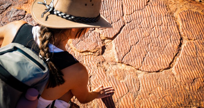 A traveller touching the rock ripples of a once-sandy ocean bed at Kings Canyon in the Northern Territory