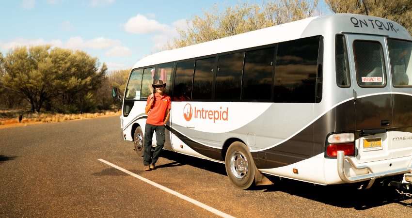 An Intrepid leader standing and smiling by a small coach