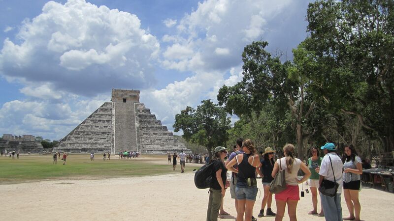 A group of travellers standing together with Chichen Itza in the background