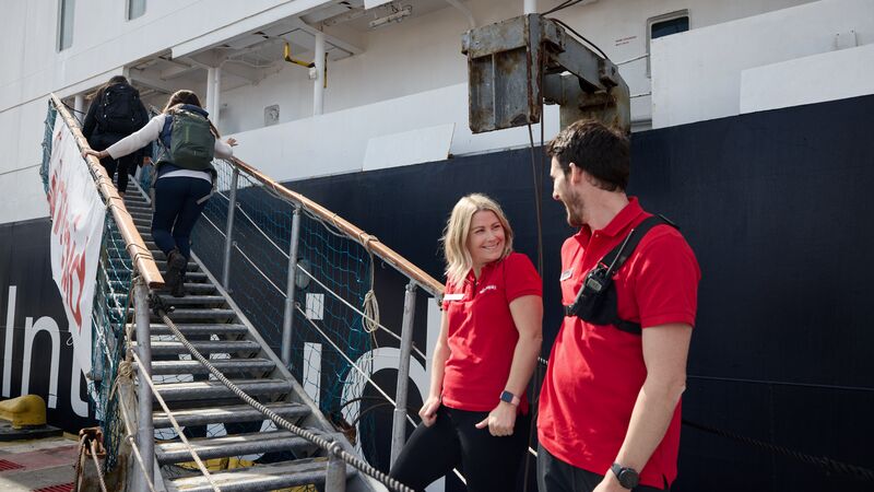 Two Intrepid crew members welcoming passengers onboard the Ocean Endeavour. 