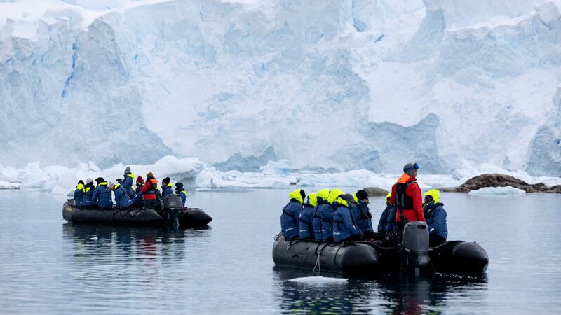 Two zodiac boats full of passengers heading to the shores of the Antarctic Peninsula.