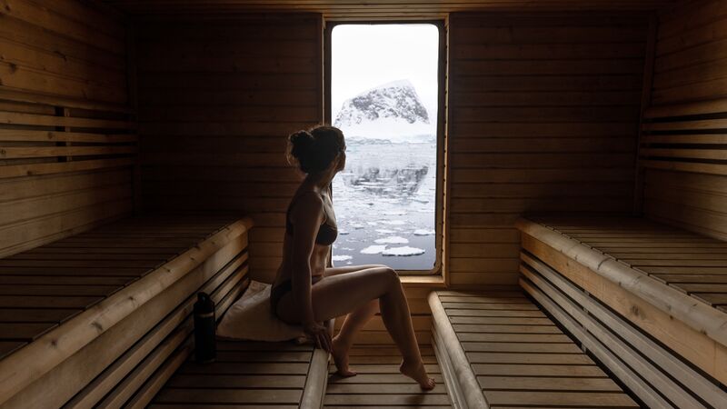 A woman enjoying a sauna onboard the Ocean Endeavour with icy landscapes through the window.