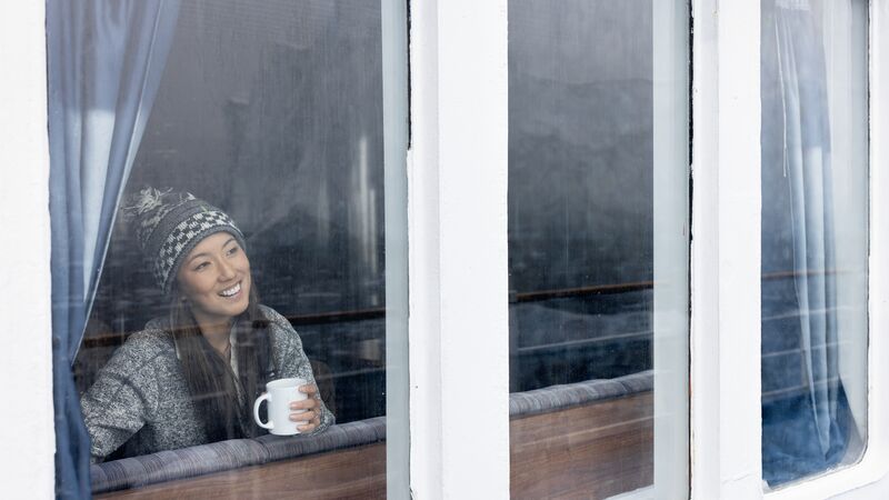 A woman looks out of her cabin window at the Antarctic landscape. 