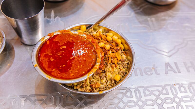 A heaped bowl of traditional food with a side dipping sauce in Egypt.
