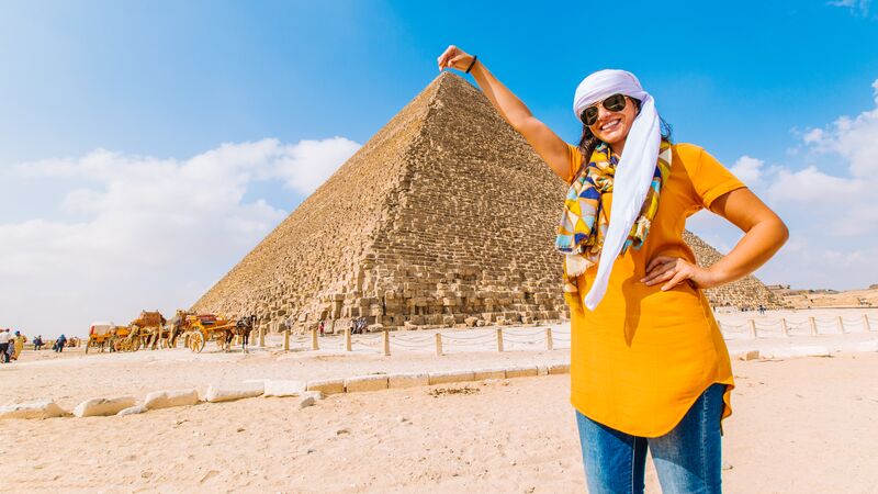 A woman traveller posing for a photo with one of the pyramids of Giza in Cairo. 
