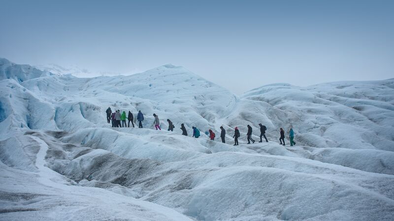 A line of travellers walking over an incy landscape in Patagonia, Argentina