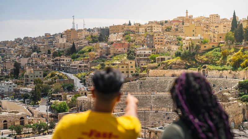 Two travellers pointing at an archeoloical structure in Amman, Jordan.