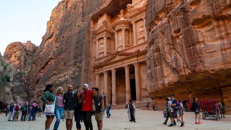 A group of travellers posing for a photo in front of a sandstone carved monument.