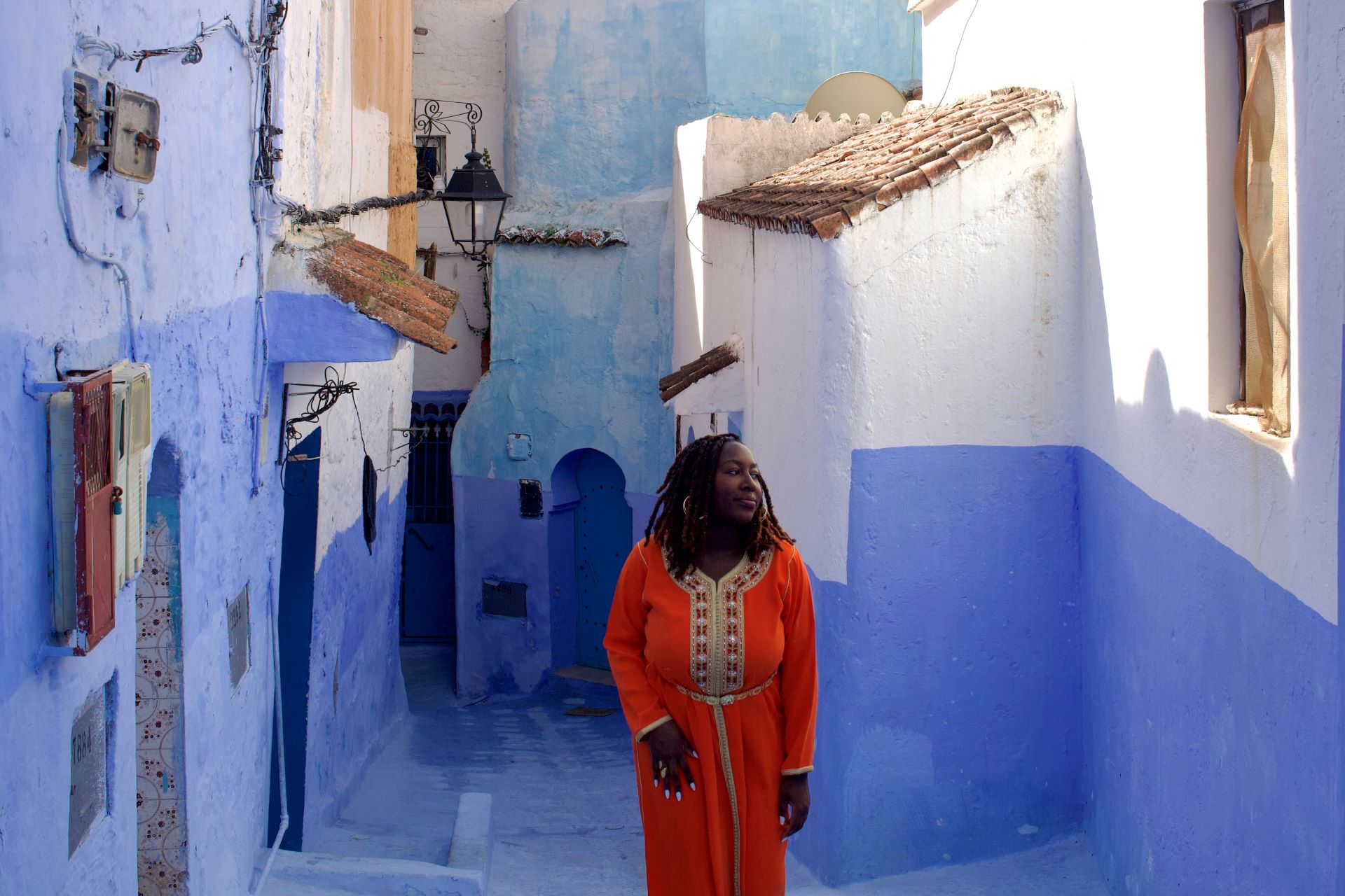 a black woman walking through an old Moroccan city that's blue