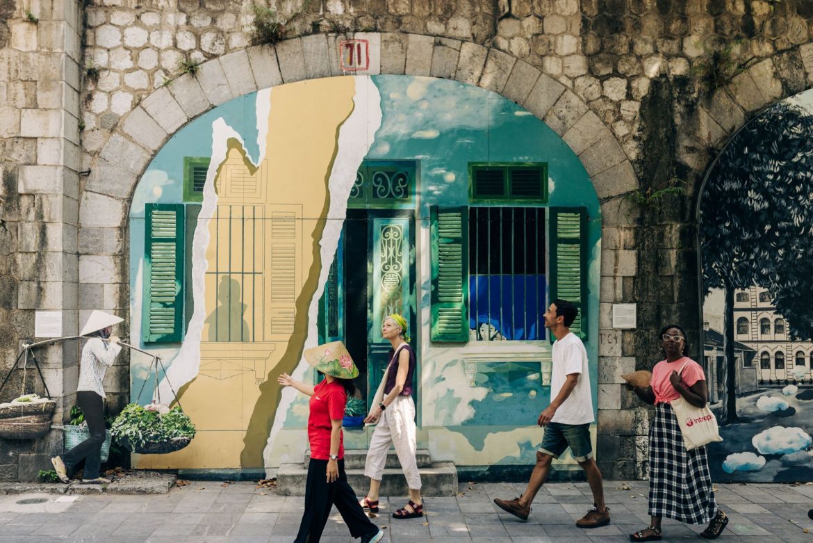a group of travellers walking in front of a mural in Hanoi