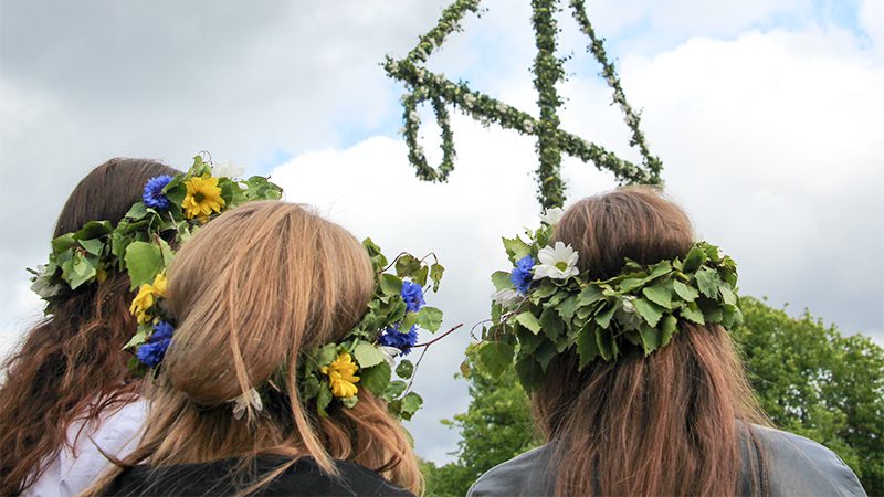 Three women wearing traditional flower crowns for Swedish Midsummer celebrations