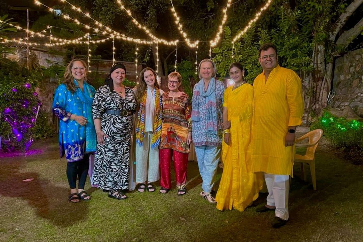 a group of travellers standing with their Indian hosts under fairy lights
