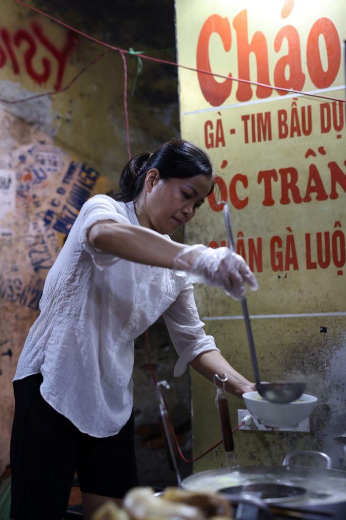 a market vendor ladles pho into a bowl